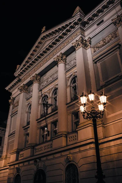 Prag Stavovsk divadlo 'nun muhteşem gece manzarası, sıcak sokak lambalarıyla aydınlatılıyor ve tarihi şehir merkezinde zarif klasik sütunları, süslemeleri ve rafine edilmiş mimari simetrisiyle sergileniyor..