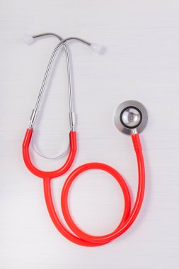 Kırmızı steteskoplu kırmızı kalp beyaz ahşap arka planda izole edilmiş. Tıbbi konsept, sağlık hizmeti konsepti.