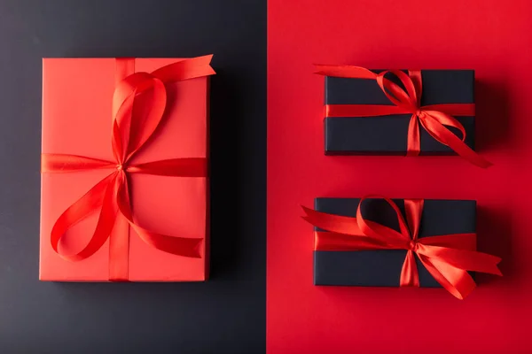 1 Big Red gift box with red ribbon on half red color background and 2 black gift box on half black color background. 11.11 single day, Monday, Friday sale concept