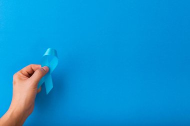 Mavi kurdele farkındalığı, kopyalama uzayı olan mavi bir arkaplanda elle izole ediliyor. Dünya Diyabet Günü. Sağlık ve Tıp Konsepti