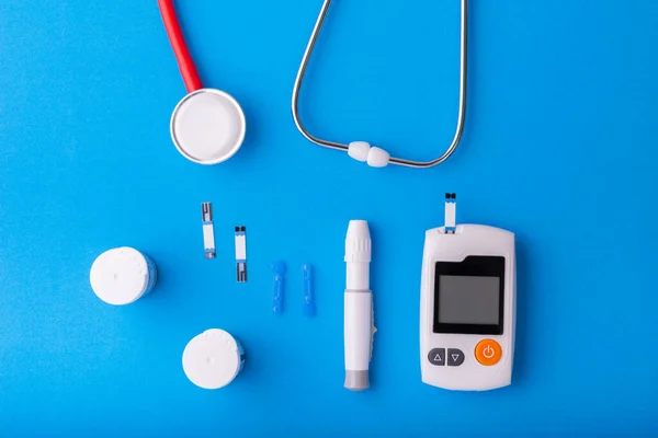 World diabetes day, Free Glucose Monitors on blue background with red Stethoscope put on blue on  top view Healthcare and medical concept