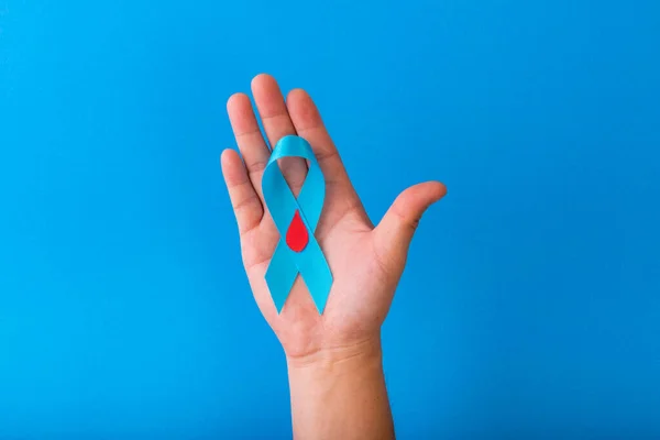 Mavi kurdele farkındalığı, kopyalama uzayı olan mavi bir arkaplanda elle izole ediliyor. Dünya Diyabet Günü. Sağlık ve Tıp Konsepti