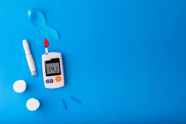 Dünya Diyabet Günü, mavi arka planda kırmızı kan damlası olan Mavi kurdele mavi arkaplandaki monitörlerde glikoz seviyesi üzerinde. Sağlık ve Tıp Konsepti