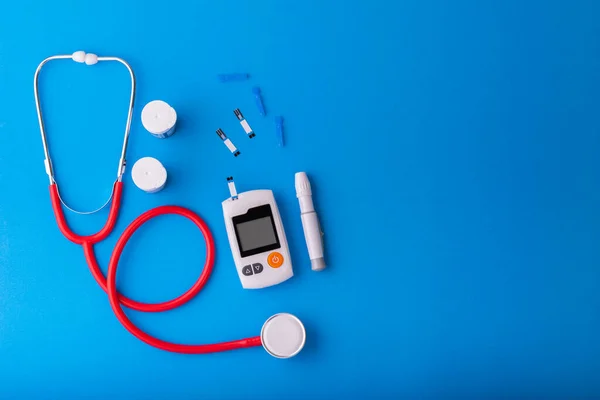 World diabetes day, Free Glucose Monitors on blue background with red Stethoscope put on blue on top view. Healthcare and medical concept