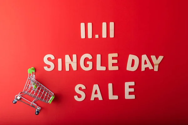 11.11 Single day sale. Small cart with 11.11 single\'s day sale text was made from wood on red color background. Top view