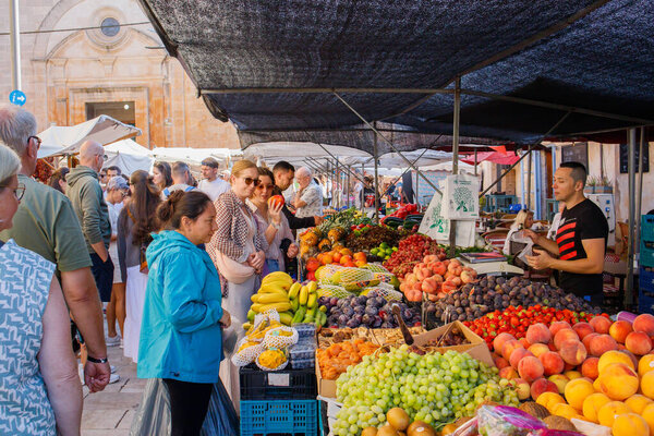 Tourists buying fresh fruits sold on regular street market in Santanyi on Mallorca island in Spain in October