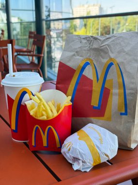 McDonald 's dışarıdaki teras masasından sipariş verdi. Markalı kese kağıdı, taze patates kızartması, hamburger ve içki. Polonya 'da eski tarz paket tasarımı