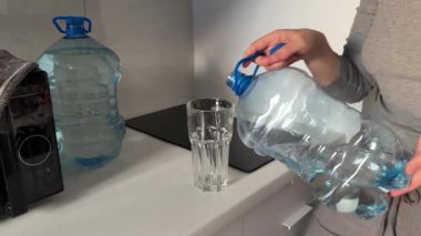 Büyük şişeden bardağa kadar bardağa temiz içme suyu dökme işlemi.