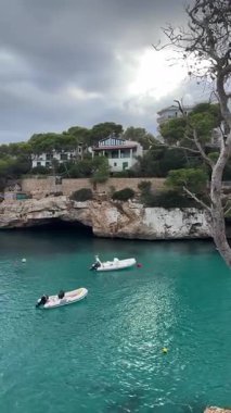 Mallorca, İspanya 'daki Cala Santanyi körfezi. Ada kıyılarına demirlemiş yatlar ve bir sürü motorlu tekne..