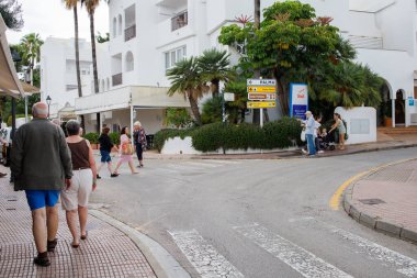 İspanya 'nın Mallorca adasındaki Cala D' Or kasabası. İspanya 'nın turistik tatil köyünün sokaklarında yürüyen turistler.