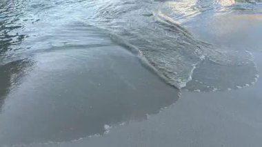 Kumlu sahil manzarasında dalgalar ve deniz köpüğü