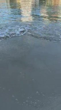 Kumlu sahil manzarasında dalgalar ve deniz köpüğü