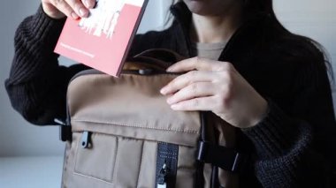 Kadın sırt çantasına güvenlik rehberi kitapçığı koyuyor. Polonya 'da kamu güvenliği kuralları