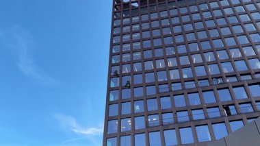 Bir iş merkezinin yüksek binasının camlarını temizleyen iki endüstriyel tırmanışçı. Yükseklik ve modern yapı konusunda tehlikeli bir çalışma..