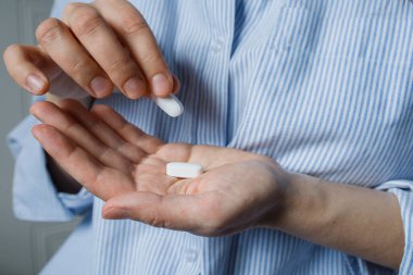 Kadınların elinde iki büyük beyaz tablet. Evde ilaç almak, hastalık önleme, antidepresan almak..