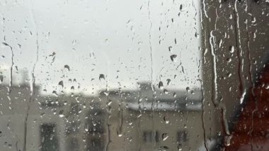 Şehir dairesinin cam penceresine yağmur damlaları düşer. Kötü yağmurlu karamsar hava, hüzünlü hava, sakinlik ve rahatlama..
