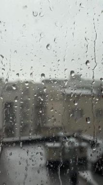 Şehir dairesinin cam penceresine yağmur damlaları düşer. Kötü yağmurlu karamsar hava, hüzünlü hava, sakinlik ve rahatlama.