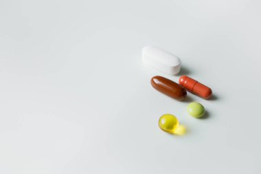 Beş farklı renkli hap, tablet ve kapsül beyaz arka plana kapanıyor. Sağlık ve ilaç sektörü, ilaç endüstrisi. Vitaminler ve takviyeler, evde tedavi.