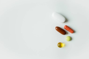 Beş farklı renkli hap, tablet ve kapsül beyaz arka plana kapanıyor. Sağlık ve ilaç sektörü, ilaç endüstrisi. Vitaminler ve takviyeler, evde tedavi.