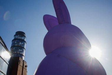 Güneşli bir bahar gününde şehir merkezinde dikilen devasa, şişme menekşe Paskalya tavşanı heykeli kapanıyor. Geleneksel Paskalya kutlamaları şehir dekorasyonu.