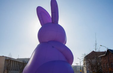 Şehir merkezinde duran devasa şişme mor Paskalya tavşanı heykeli. Geleneksel Paskalya kutlamaları şehir dekorasyonu.