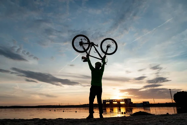 Der Radler jubelt über den Sieg am Ufer des Sees. — Stockfoto