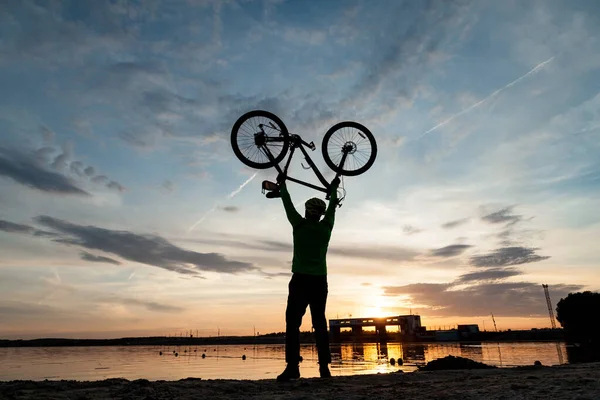 Велогонщик радуется победе на берегу озера. Стоковая Картинка
