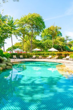 Otelde ve tatil beldesinde yüzme havuzunda güzel şemsiye ve sandalye - tatil kavramı