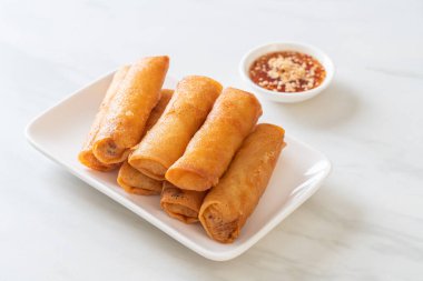 Kızarmış yumurta rulosu ve beyaz tabakta sos.