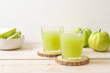 Taze guava suyu bardağı ve ahşap masada taze guava meyvesi.