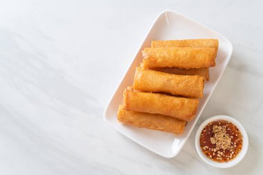 Kızarmış yumurta rulosu ve beyaz tabakta sos.