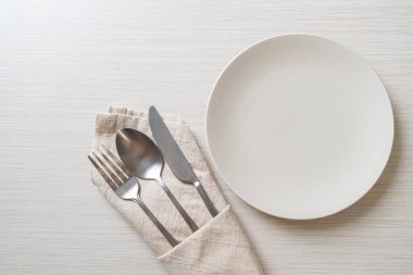 Ahşap zemin üzerinde bıçak, çatal ve kaşık olan boş tabak veya tabak
