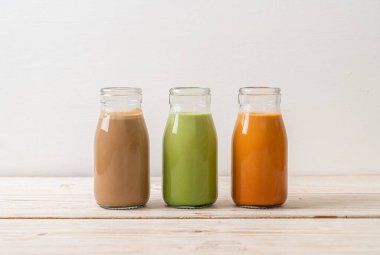 Tayland sütlü çay koleksiyonu, ahşap arka planda yeşil çay ve kahve şişesi.