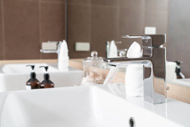 Modern metalik musluğun banyodaki yakın çekimi.