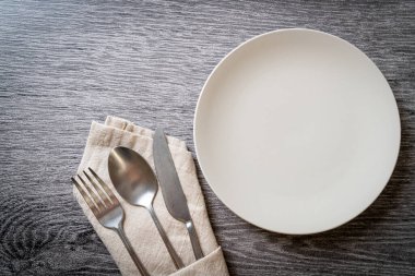Ahşap zemin üzerinde bıçak, çatal ve kaşık olan boş tabak veya tabak