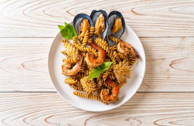 Deniz ürünleri ve fesleğen soslu kızarmış spiral makarna. Füzyon yemek tarzı.