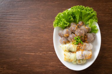 Şeffaf toplara Saku Sai Moo ya da Buharlı Tapioca Köfte Topları ve (Kow Griep Pag Mor) Domuz Buharlı Pirinç Paketleri ya da Haşlanmış Pirinç Kabuklu Mantı denir.