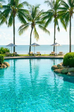 Otelde ve tatil beldesinde yüzme havuzunda güzel şemsiye ve sandalye - tatil kavramı