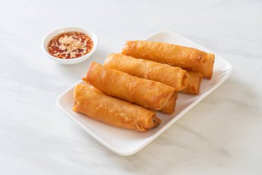 Kızarmış yumurta rulosu ve beyaz tabakta sos.