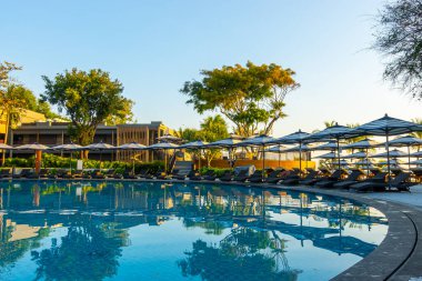 Seyahat tatili konsepti için otel tatil beldesinde yüzme havuzunun etrafında şemsiye ve sandalye.