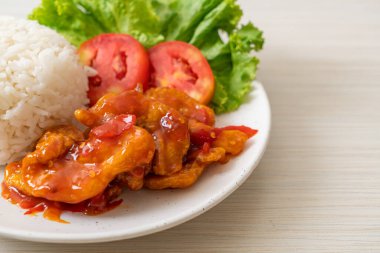 Üç çeşnili kızarmış balık. Beyaz tabakta pilav ve kırmızı biber sosu.