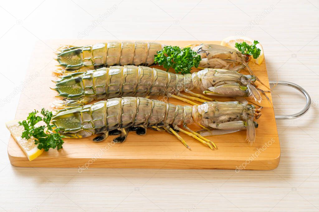 fresh mantis shrimp with lemon on wood board