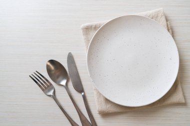 Ahşap zemin üzerinde bıçak, çatal ve kaşık olan boş tabak veya tabak