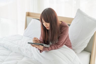 Yatakta tabletle çalışan güzel Asyalı kadınlar