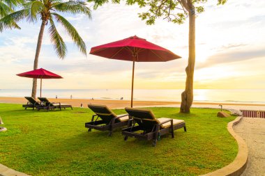 Deniz sahili geçmişi olan bir şemsiye ve sabahları gün doğumu - tatil ve tatil kavramı