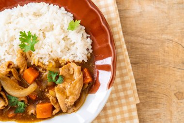 Dilimlenmiş domuz eti, havuç ve soğanlı Japon körili pilavı. Asya usulü.