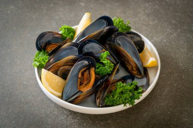 Limonlu bir kasede otlu taze midyeler.