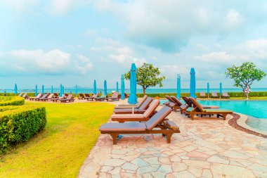 Sandalye havuzu ve şemsiyeyle okyanus arka planında yüzme havuzu