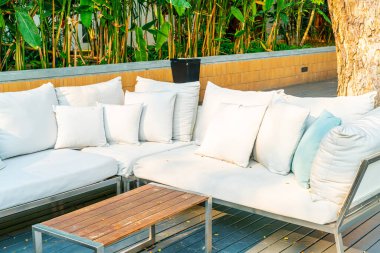 Bahçe sandalyesinde rahat yastıklar ve bahçede masa.