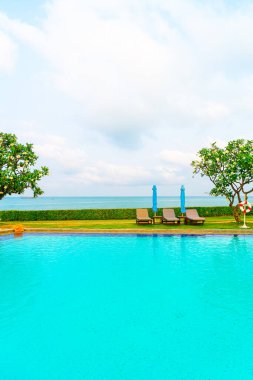 Sandalye havuzu ve şemsiyeyle okyanus arka planında yüzme havuzu